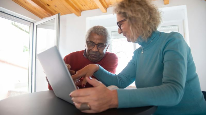 A senior care worker is looking at a tablet.